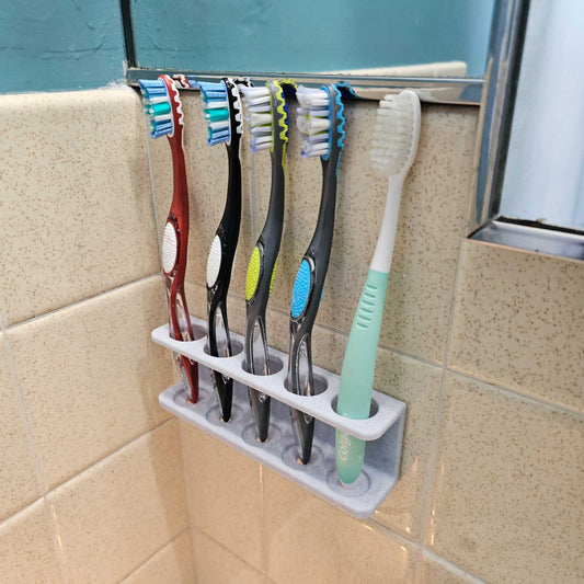 3D printable wall-mounted toothbrush holder organized with five toothbrushes in a tiled bathroom corner