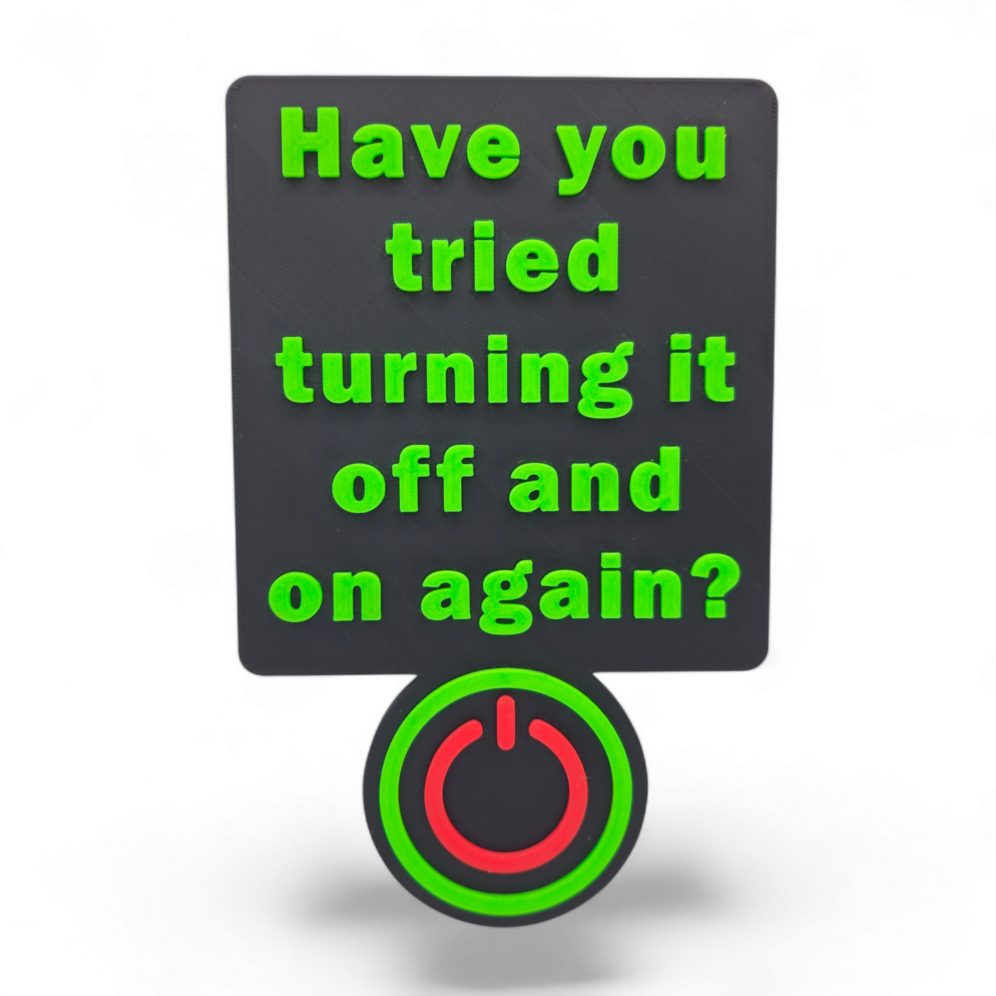 3D printable office sign with raised green text "Have you tried turning it off and on again?" and red power button detail on black background
