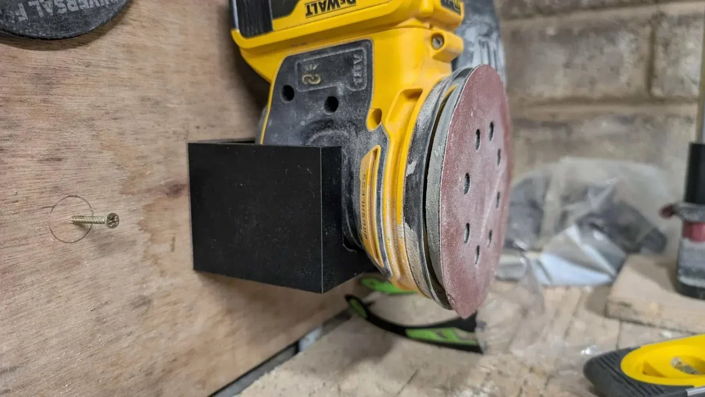 DeWalt DCW210B Wall Bracket holding yellow random orbital sander mounted on wooden wall for secure tool storage.