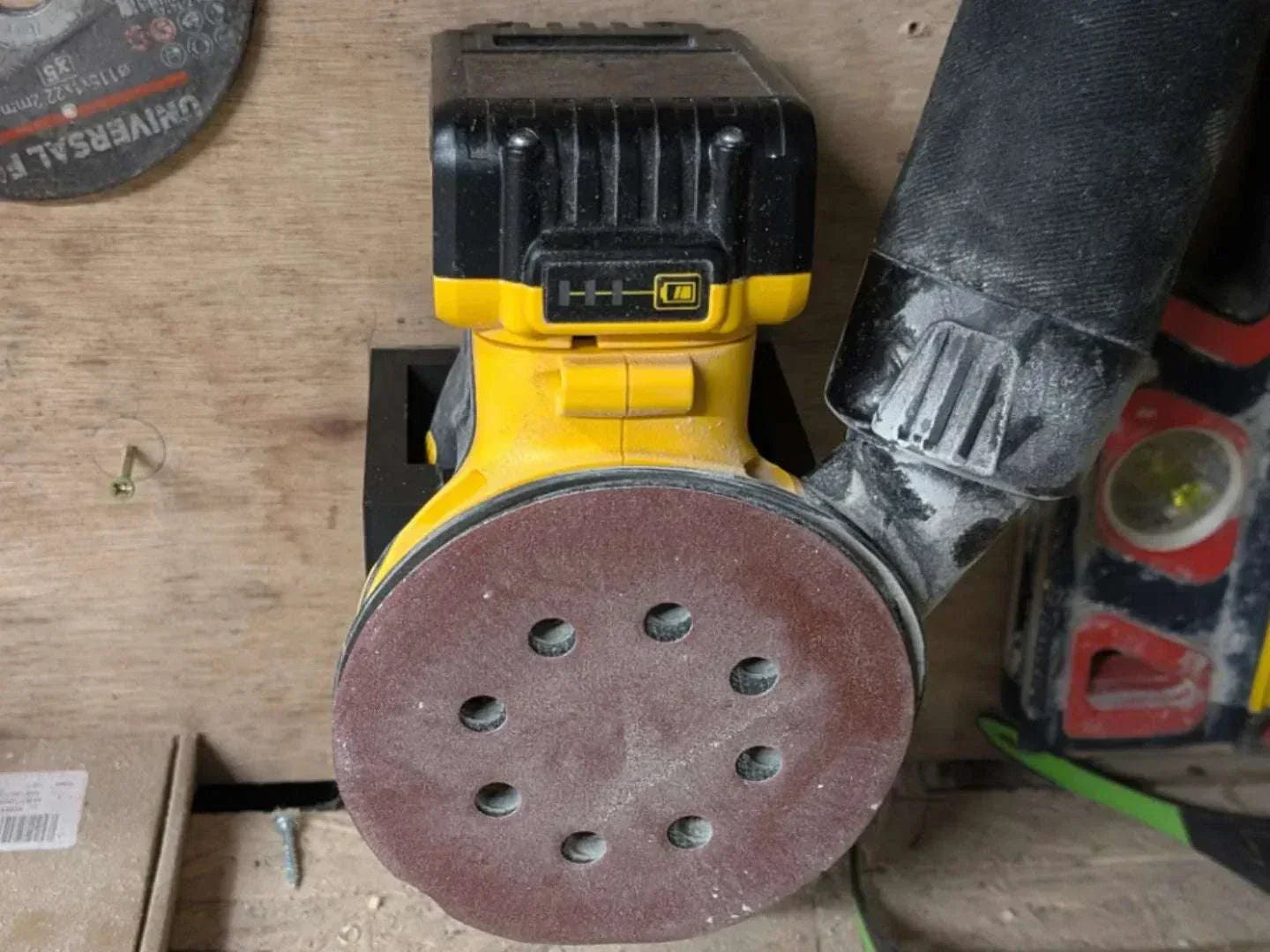 DeWalt DCW210B random orbital sander mounted on custom-fit black PETG wall bracket for secure storage.