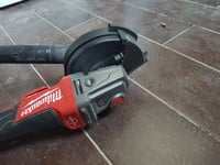 Milwaukee M18 grinder with dust collection adapter on tiled floor.